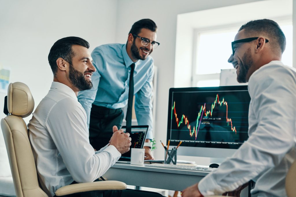 Successful Traders. Group Of Young Modern Men In Formalwear Analyzing Stock Market Data While Working In The Office